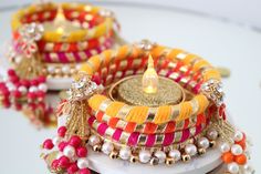 two colorful bracelets sitting on top of a table next to a candle and some beads