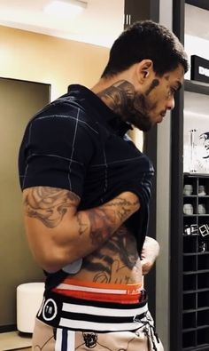 a man with tattoos on his back standing in front of a mirror