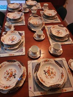 the table is set with dishes and place settings for six to eight people, all decorated in floral designs