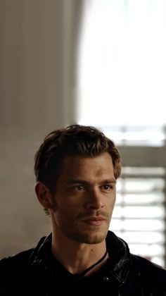 a young man in a black shirt looking at the camera with an intense look on his face