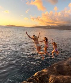 two girls jumping into the water at sunset