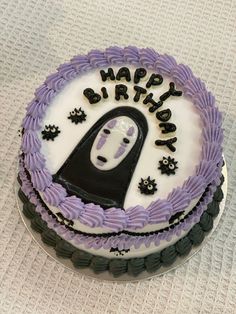 a birthday cake with purple frosting and black decorations