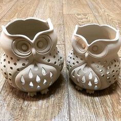 two ceramic owls sitting on top of a wooden floor