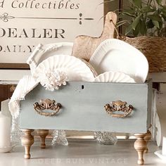 a wooden box filled with white dishes on top of a counter next to a sign