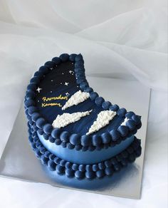 a blue cake with white stars and clouds on it's side, sitting on top of a silver platter