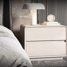 a white nightstand sitting next to a bed with a lamp on it's side