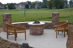 an outdoor fire pit surrounded by wooden chairs