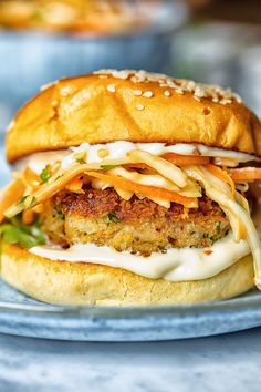 a chicken burger with cheese and sauce on a blue plate, ready to be eaten