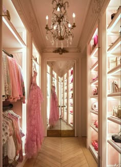 the inside of a store with pink dresses and chandelier hanging from the ceiling