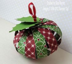 a green and red ornament sitting on top of a white table next to a wall