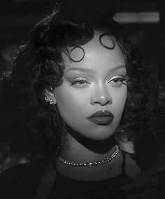 a black and white photo of a woman with curls on her hair, wearing a necklace