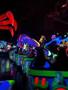 people ride on roller coasters in an amusement park at night with brightly colored lights