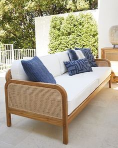 a white couch sitting on top of a patio next to a wooden table and chair