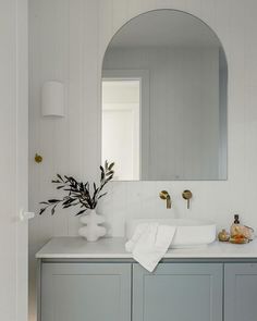 front view picture of a vanity counter with arched mirror and white countertop, above counter white basin, and warm brushed nickel tapware Coastal Hamptons Bathroom, Neptune Bathroom, Nickel Tapware, Modern Coastal Bathroom, Brass Taps, Modern Coastal Home, Powder Room Vanity, Cabinetry Hardware, Coastal Hamptons