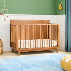 a baby crib in the corner of a room with blue carpet and green walls