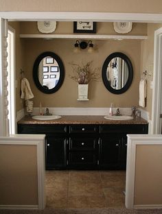 a bathroom with double sinks and mirrors on the wall above them is seen through two doorways