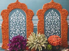 flowers and plants are sitting in front of an intricately decorated wall