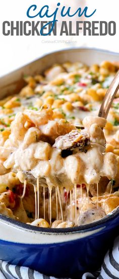 a casserole dish filled with chicken alfredo and cheese is being lifted by a wooden spoon