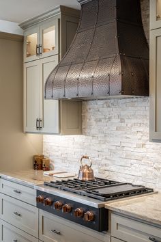 a stove top oven sitting inside of a kitchen next to white cupboards and drawers