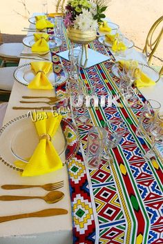 the table is set with yellow napkins and place settings