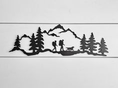 a metal wall hanging with people and animals in the woods