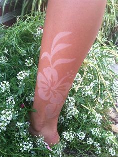 a person's legs with white paint on them and flowers in the foreground