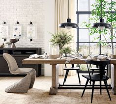 a dining room table with chairs and plants in the center, next to an open window