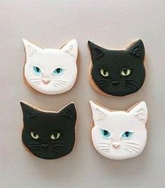 four decorated cookies in the shape of cats with blue eyes and black, white, and yellow faces