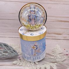 a snow globe sitting on top of a blue box next to a silver and gold christmas ornament