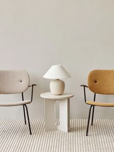 two chairs sitting next to each other on top of a carpeted floor in front of a white wall