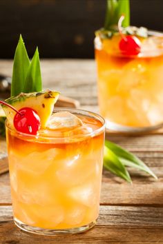 two glasses filled with drinks sitting on top of a wooden table