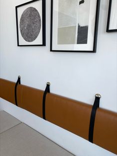 three black and white pictures hang on the wall next to two brown leather bench seats