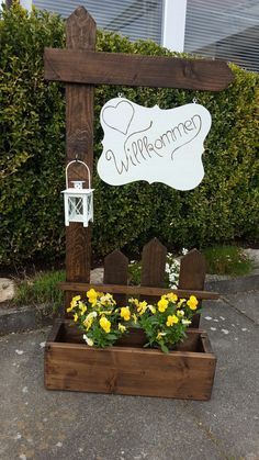 a wooden sign that says welcome to someone with flowers in the planter below it