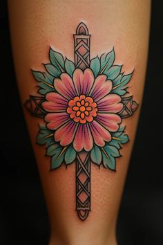 a woman's leg with a cross and flower tattoo on it