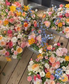 several flower arrangements arranged on a wooden floor