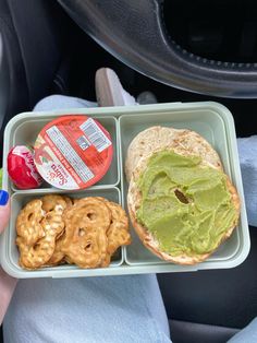 a person is holding a tray with some food in it and there are pretzels on the side