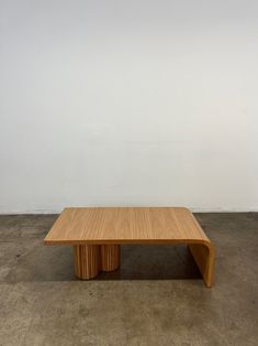 a large wooden table sitting on top of a cement floor next to a white wall