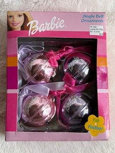 the packaging for barbie dolls is pink and has purple ribbon around its bows, which are attached to each other