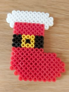 a red and black beaded santa clause ornament on a wooden table top