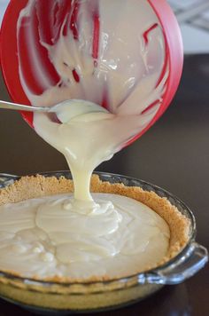 a person pouring white sauce on top of a pie