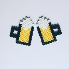 two beer mugs made out of lego bricks on a white surface, one is yellow and the other is black