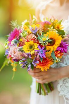 a woman holding a bouquet of colorful flowers