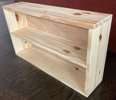 a wooden shelf sitting on top of a hard wood floor next to a red wall