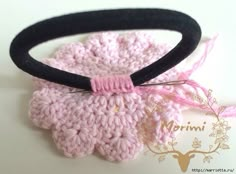 a crocheted pink and black hair tie on top of a white table next to a deer head