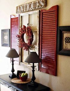 an entryway with red shutters and a wreath on the wall next to two lamps