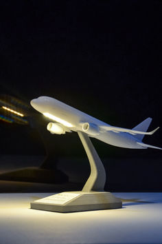 a model of an airplane on display in a dark room with light coming from behind it