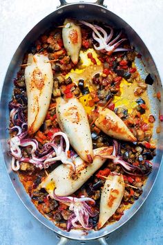 a pan filled with fish and vegetables on top of a table