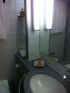 a bathroom with a sink, mirror and toilet paper dispenser in it