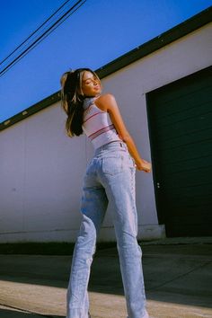 a woman in high waisted jeans is posing for the camera