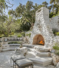 an outdoor fireplace and seating area with stone walls